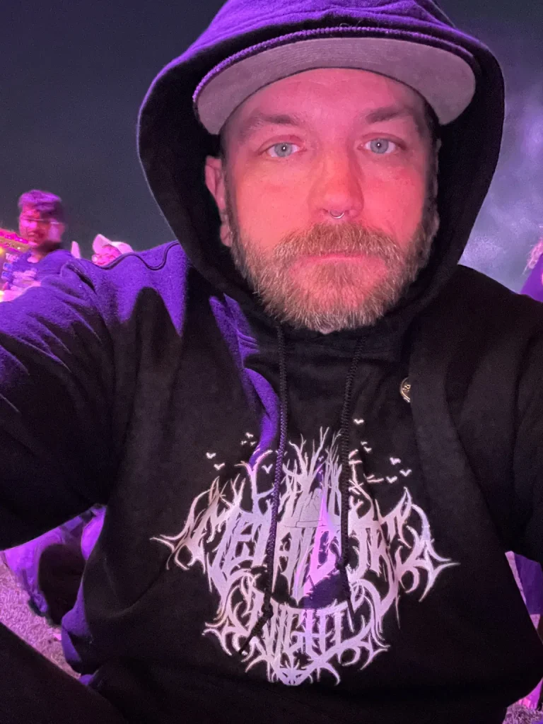 Adam Rahuba, founder of Metalcore Night, wearing a hoodie with the Metalcore Night logo at a live concert.